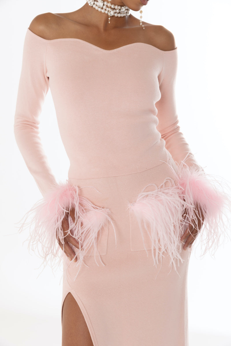 Pink vanilla knit midi skirt with feather accents by Andreeva, shown on a model with a flowing, stylish design.