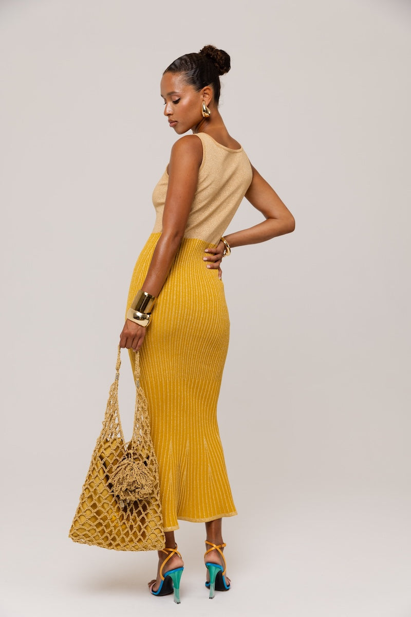 Golden Hour metallic knit maxi dress by Andreeva displayed on a hanger, showcasing its shiny gold fabric and elegant design.