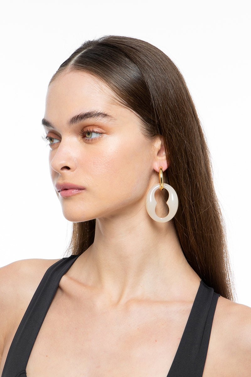 Gold and rice-colored earrings by Silvia Gnecchi featuring ULU design, shown in a close-up image.