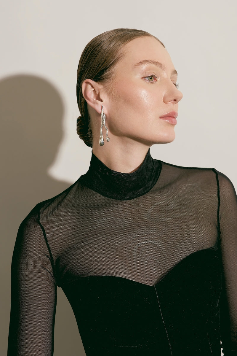 Silver Eugenia Ospina Origen earrings with intricate design and polished finish displayed against a neutral background.