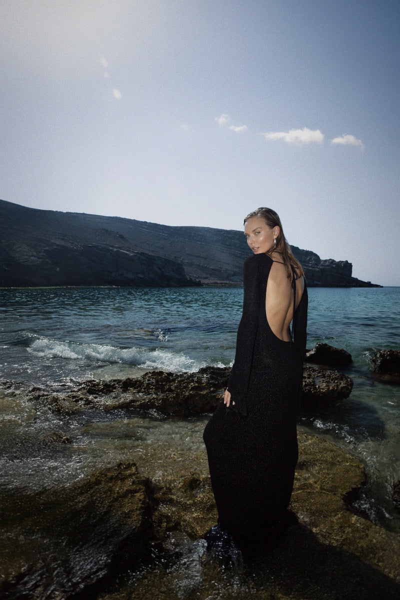Black OLYA maxi dress by Suncillo with flowing fabric and elegant design, shown on a model in a stylish outdoor setting.
