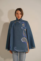 Nadya Shah Olympia denim cape jacket displayed on a hanger, showcasing its stylish, lightweight denim design with a relaxed fit.