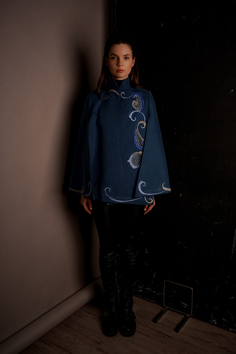 Nadya Shah Olympia denim cape jacket with classic blue denim, stylish design, and button details, displayed on a neutral background.