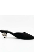 Black Orbit heels by Yassmin Saleh featuring sleek design and pointed toes, displayed on a ghost inside background.
