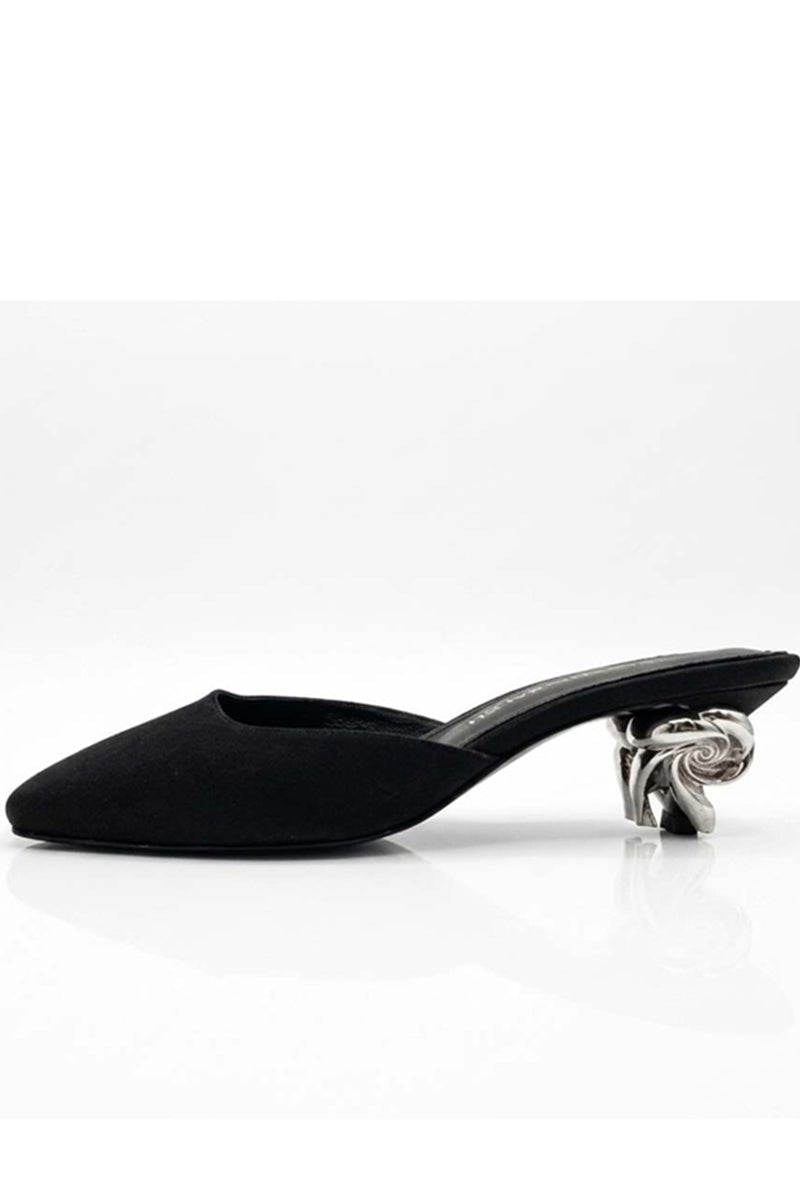 Black Orbit heels by Yassmin Saleh featuring sleek design, pointed toes, and stiletto heels, displayed outdoors.
