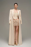 Beige double-breasted long coat by I.H.F Studio featuring an oversized, straight-cut design, displayed on a hanger.