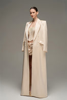 Beige double-breasted long coat by I.H.F Studio with an oversized, straight-cut design shown on a model.