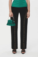 Black JC Pajares long eyelets pants with metal eyelet details and a slim fit, shown hanging on a white background.