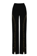 Black long eyelets pants by JC Pajares featuring eyelet details and a sleek, fitted design shown on a model.