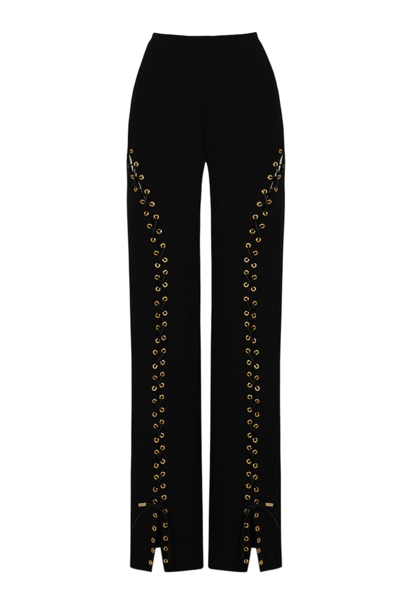 Black long eyelets pants by JC Pajares featuring eyelet details and a sleek, fitted design shown on a model.