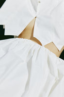 White tiered midi skirt by PODYH, featuring flowing fabric and layered design, perfect for casual or dressy looks.
