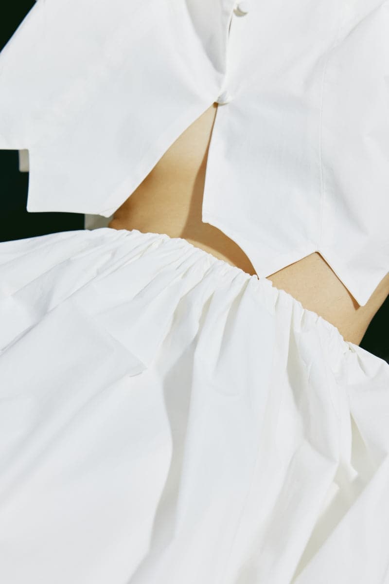 White tiered midi skirt by PODYH, featuring flowing fabric and layered design, perfect for casual or dressy looks.