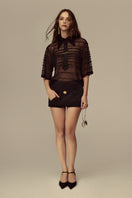 POEM Marabel mini skirt in black fabric, featuring a fitted waistband and short hem, styled with casual top and accessories.