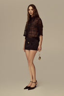 POEM Marabel mini skirt in black with a fitted waist and short hem, styled with casual top and sneakers.