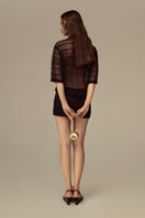 POEM Marabel mini skirt in black with a fitted waist and short hem, styled with casual top and accessories.