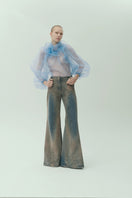 NADYA DZYAK flared jeans in rusty denim with high waist and wide leg, displayed on a model in a stylish fashion pose.