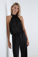 Serenity Palermo black silk-satin halter jumpsuit displayed on a hanger, featuring a sleek design and halter neckline.