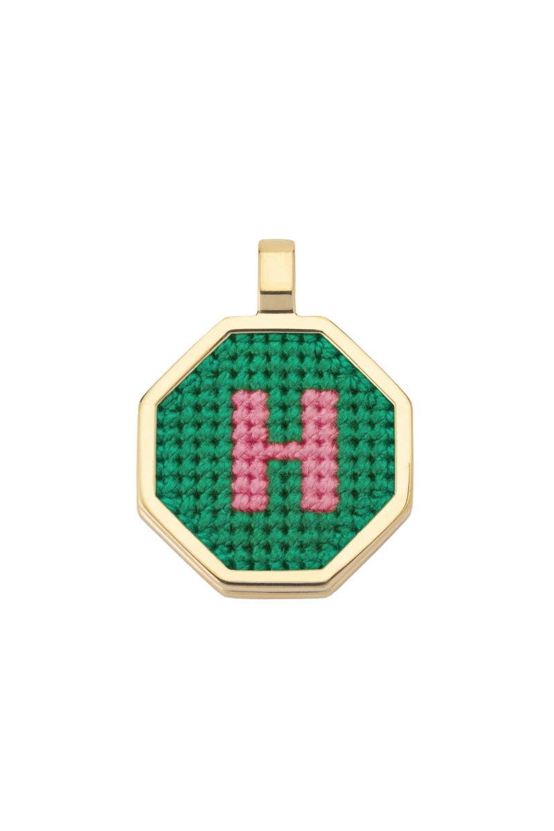 Personalised letter pendant necklace by Maria Frering with a green charm, close-up of the customized jewelry piece.