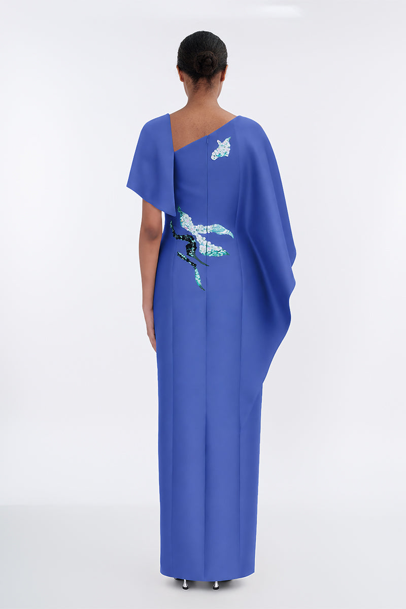 Elegant petal-colored asymmetrical evening gown with a cape, designed by Tiny Ink, featuring flowing fabric and stylish draping.