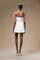 Ivory Petalia mini skirt by ANA + MARIA, shown on a hanger with a soft fabric texture and a stylish, fitted silhouette.