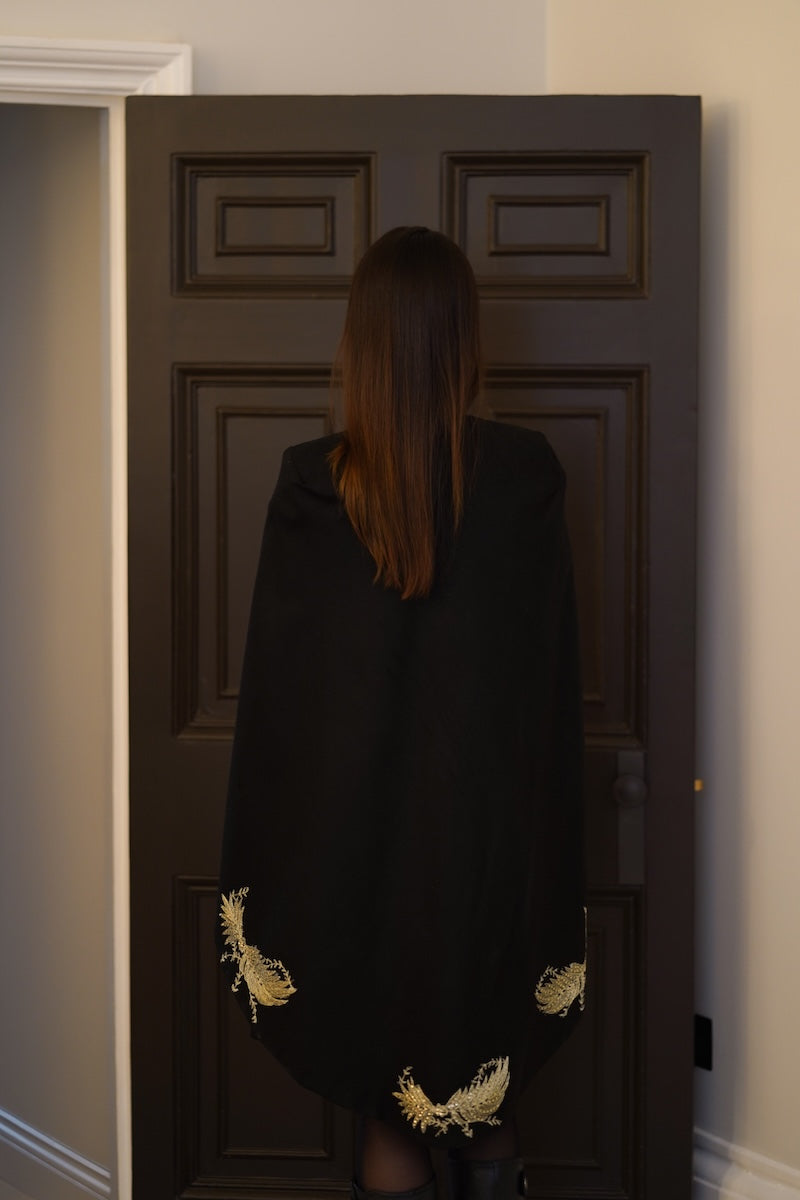 Nadya Shah Phoebe Cape jacket with a draped design, shown from the back in a stylish, versatile outerwear look.
