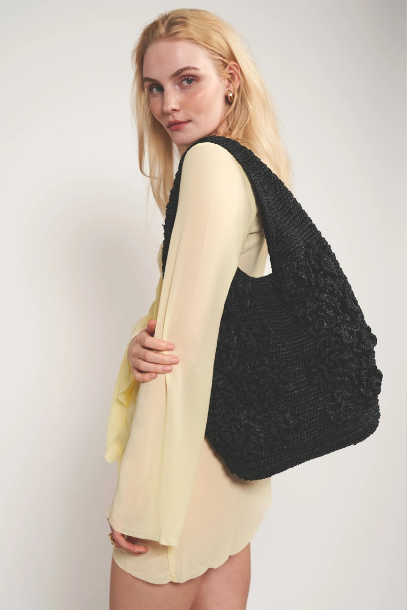 Emm Kuo Pinet shoulder bag in black, featuring a sleek design and spacious interior, shown in a large image.