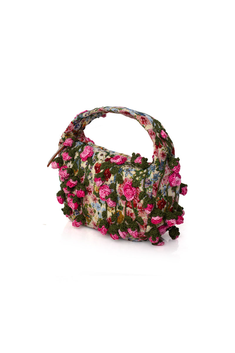 Pink roses design on Sarah's Bag Le Petit top handle bag with pink floral pattern and elegant handles.