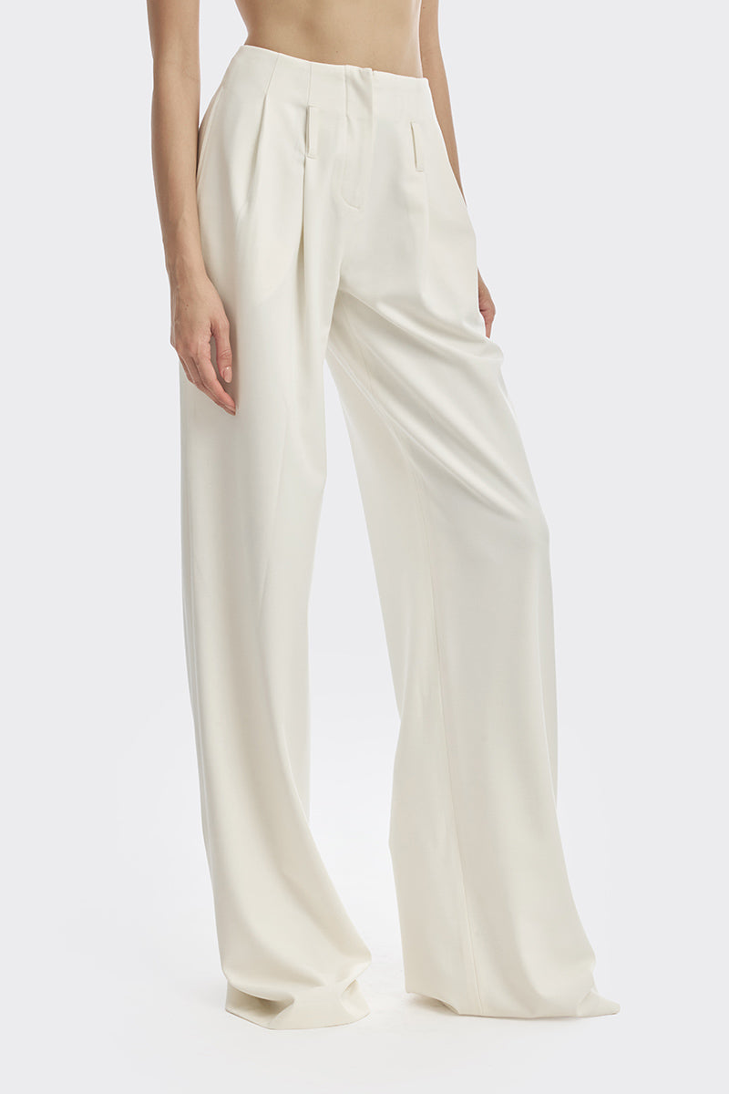 Off-white pleated trousers by Stolen Stores featuring a tailored fit and classic design, displayed on a white background.