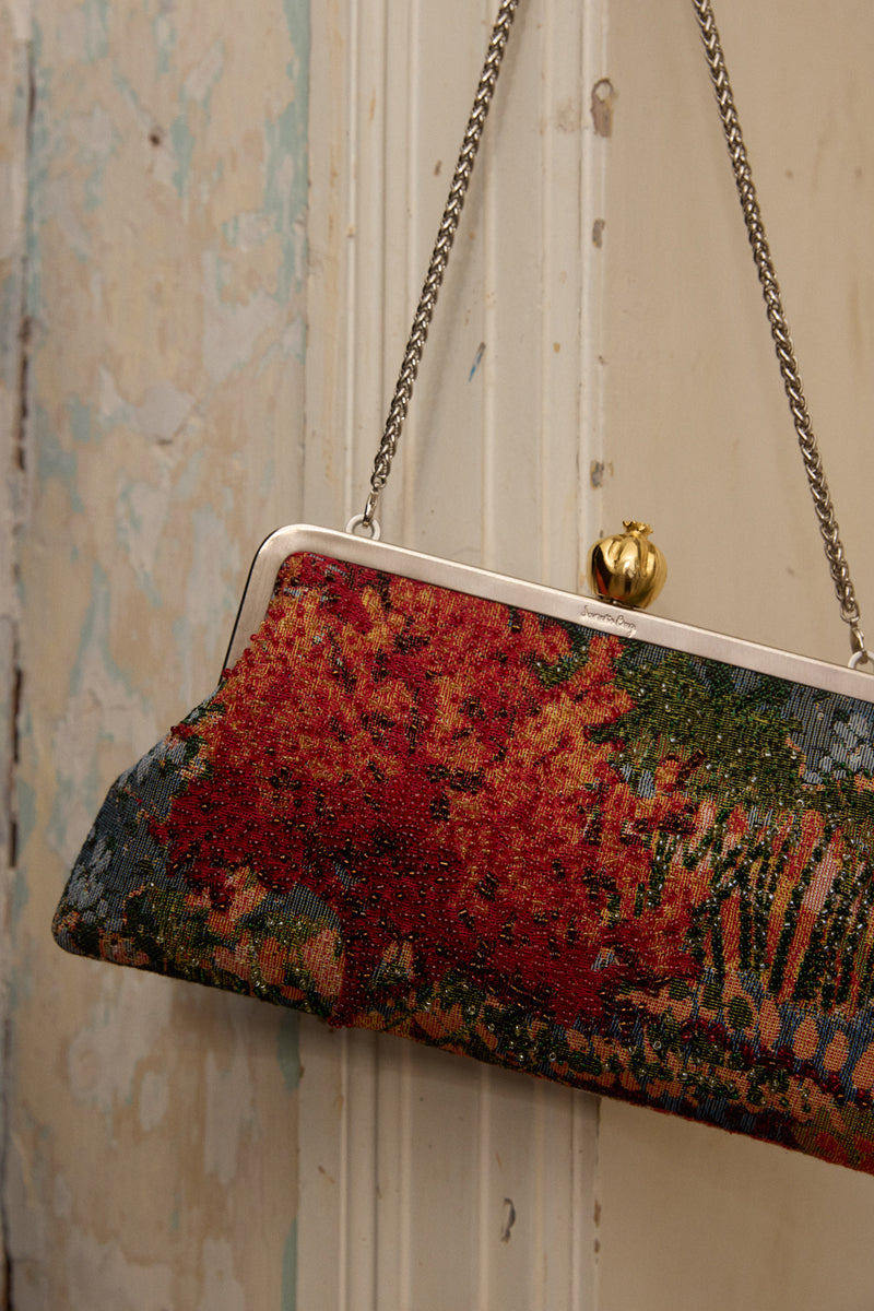 Multicolor pomegranate on autumn field design clutch bag by Sarah's Bag, featuring vibrant fruit and fall landscape artwork.