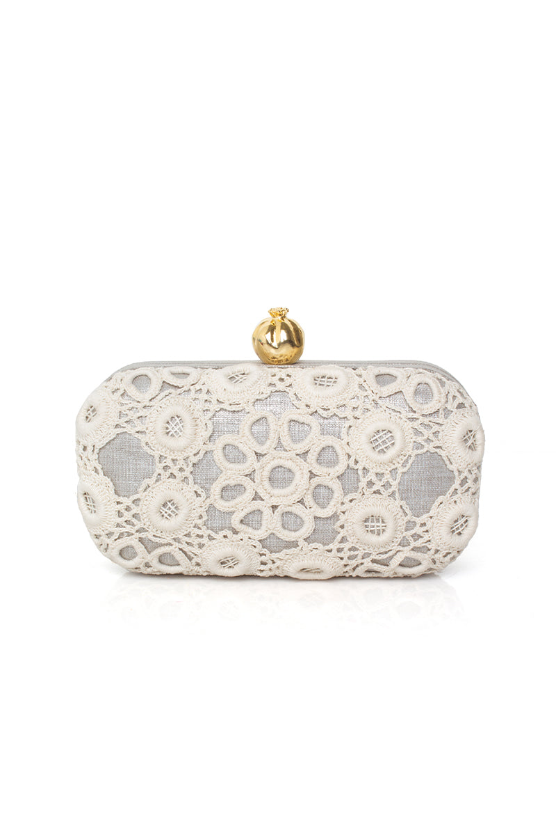 Silver clutch bag by Sarah's Bag featuring a detailed crochet pomegranate design on a sleek silver box.
