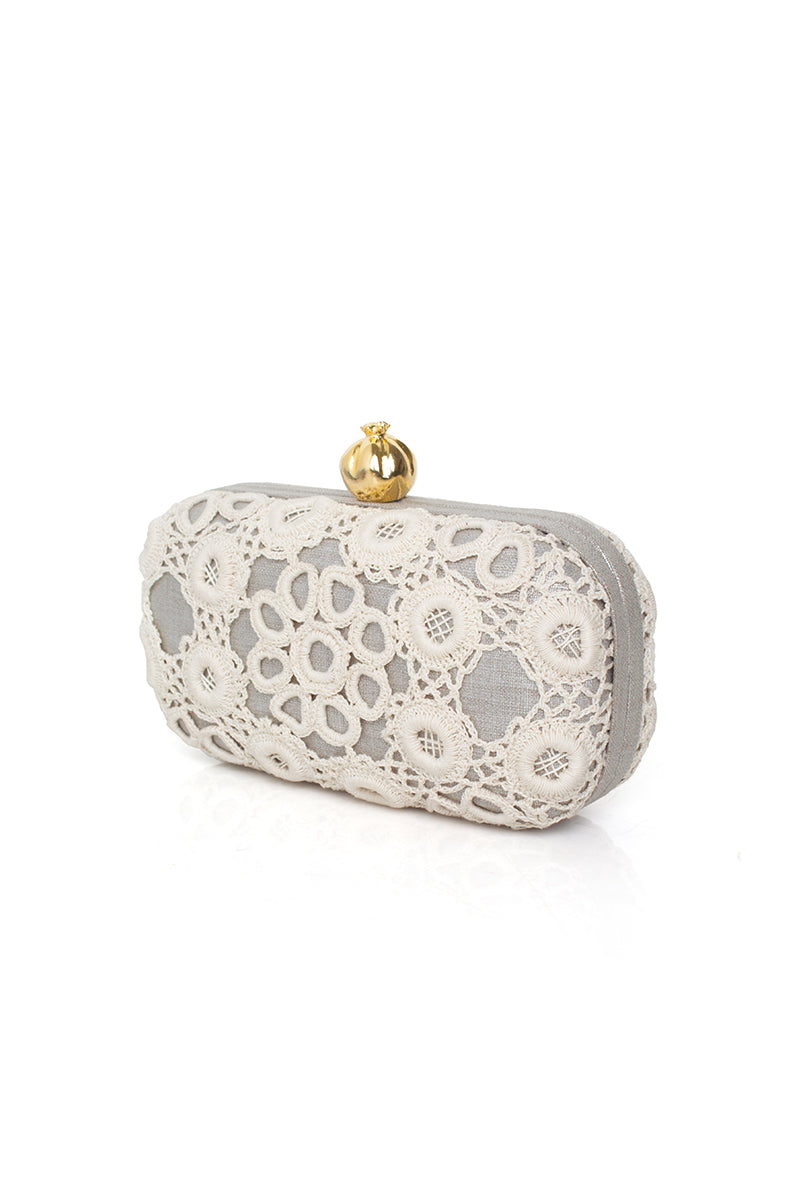 Silver clutch bag by Sarah's Bag featuring a crocheted pomegranate design on a sleek silver box.