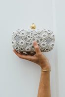 Silver clutch bag by Sarah's Bag featuring a pomegranate design with crochet detailing on a sleek silver box.
