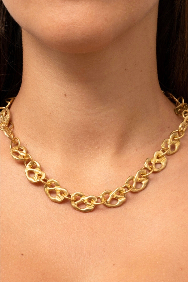 Gold pretzel mini chain necklace by Oz Objects, close-up of delicate jewelry with a detailed pretzel pendant.