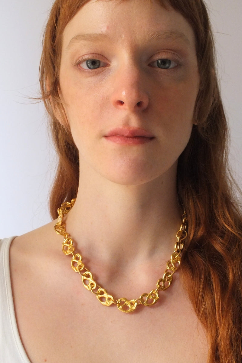 Gold pretzel-shaped mini chain necklace by Oz Objects, featuring a delicate and stylish jewelry piece.
