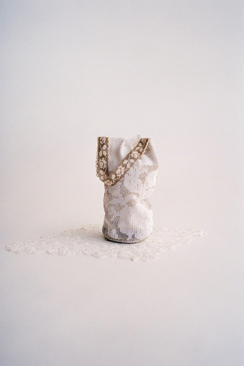 Silver lace pouch in top handle bag style by Pura Utz, featuring intricate lace details and a sleek compact design.