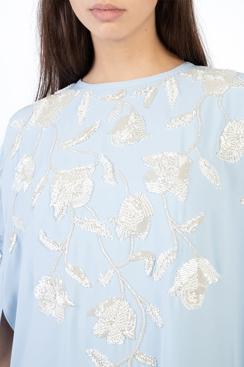 Light blue floral embellished maxi dress by Shatha Essa with intricate embroidery and flowing fabric, perfect for elegant occasions.