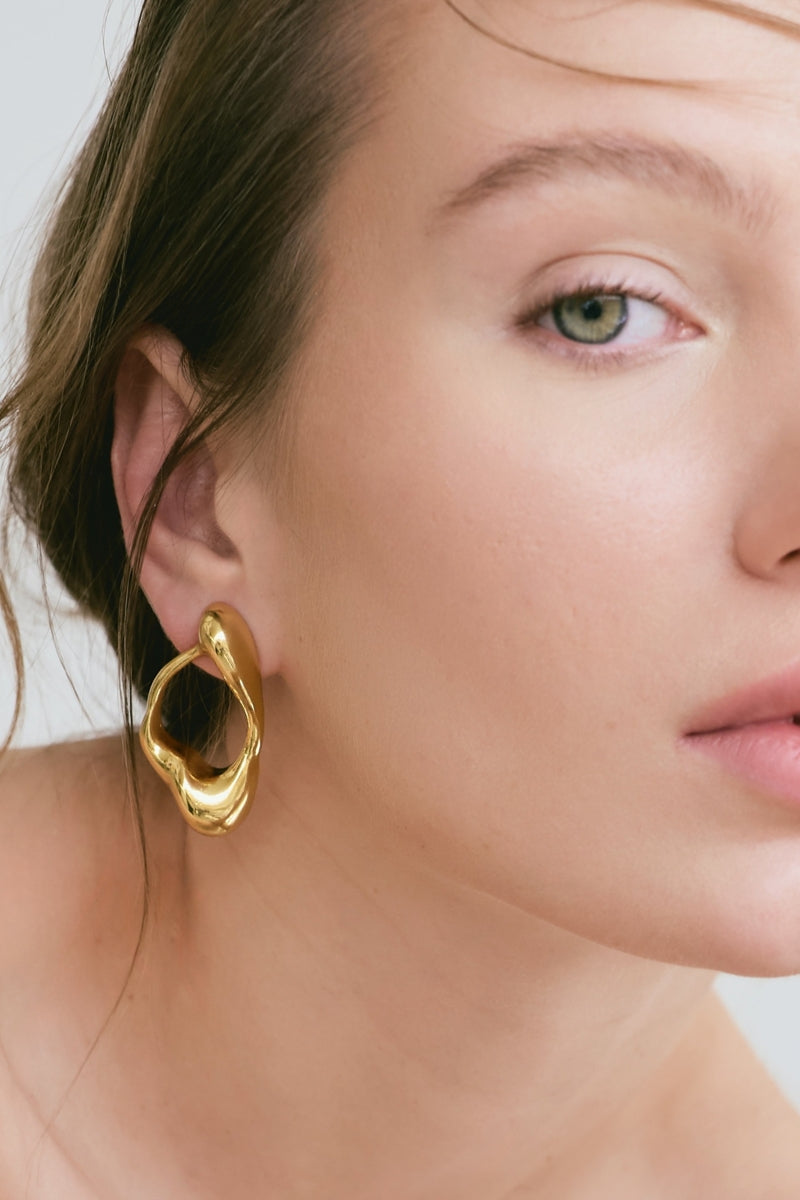 Gold earrings by Eugenia Ospina, featuring sleek and elegant design, shown on a clean background.
