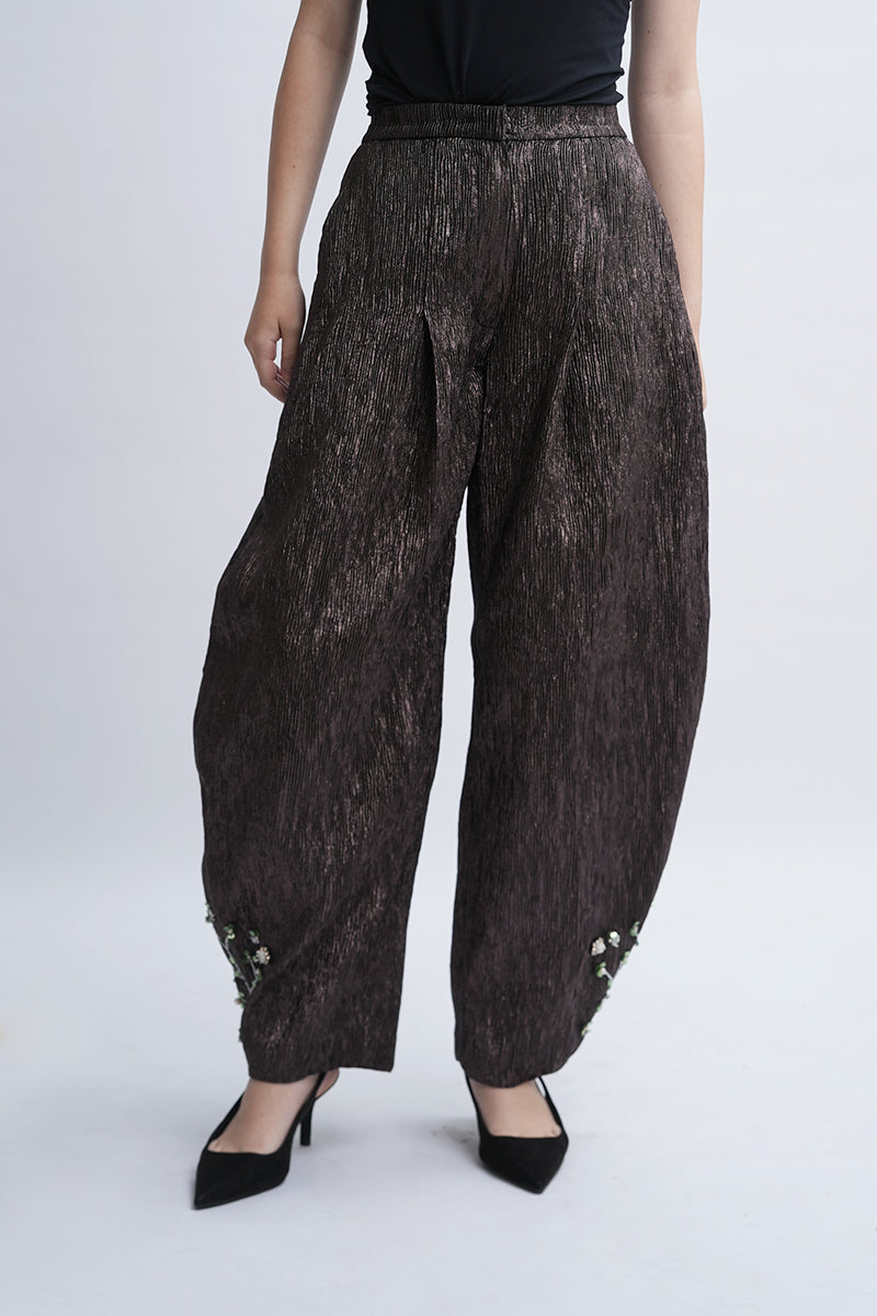 A pair of Aidan & Ice Louise Pants featuring a relaxed fit, in a neutral fabric, displayed on a wooden surface.