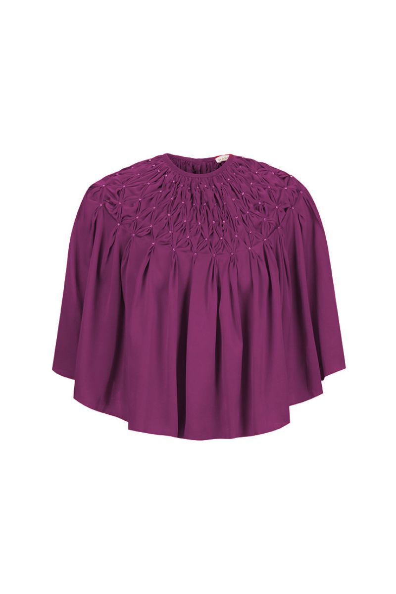 Hand-smocked aubergine cape top by Mastani, showing detailed fabric texture and stylish design on a neutral background.