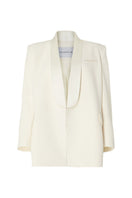 Studio NK ivory blazer from the ETHERAL collection displayed on a hanger, showcasing tailored fit and sleek design.