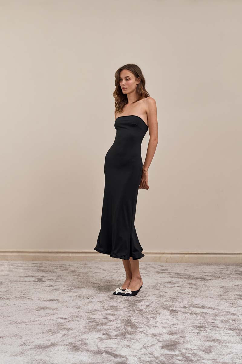 Black ripple midi dress by YASSMIN SALEH shown from a side view, highlighting its flowing fabric and elegant design.