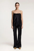 Serenity Riviera black silk satin flared pants shown on a model, featuring a high waist and flowing wide-leg design.