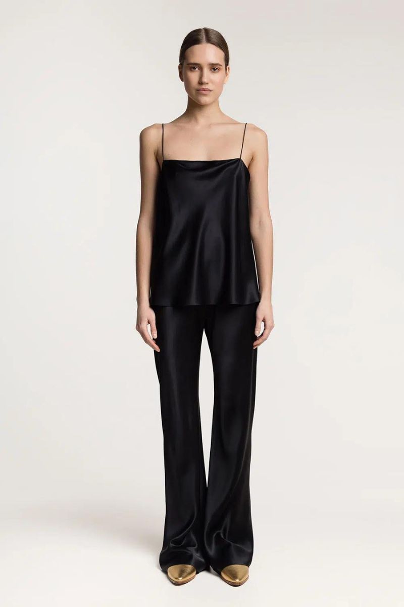Serenity Riviera black silk satin flared pants shown on a model, featuring a high waist and flowing wide-leg design.