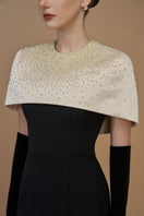 White crepe and silk taffeta cap sleeve gown with a round neck and mini cape from I.H.F, displayed in a beige and black design.