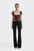 Brown ruched mini top by Stolen Stores, featuring gathered fabric and a fitted style, shown on a model.