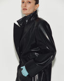 Black leather coat by Sayya featuring a classic design, shown hanging on a wooden hanger with detailed stitching visible.