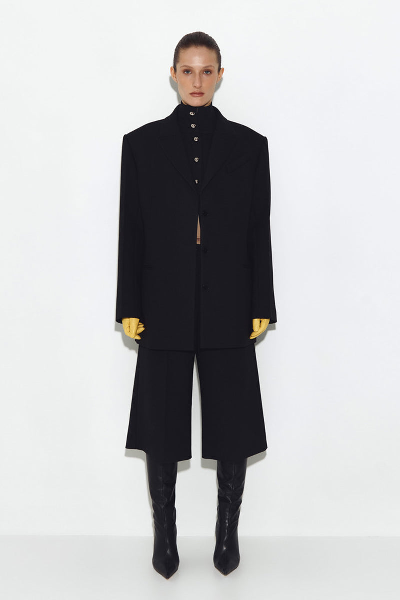 Black wool jacket from Sayya showing a close-up of the textured fabric and classic design.
