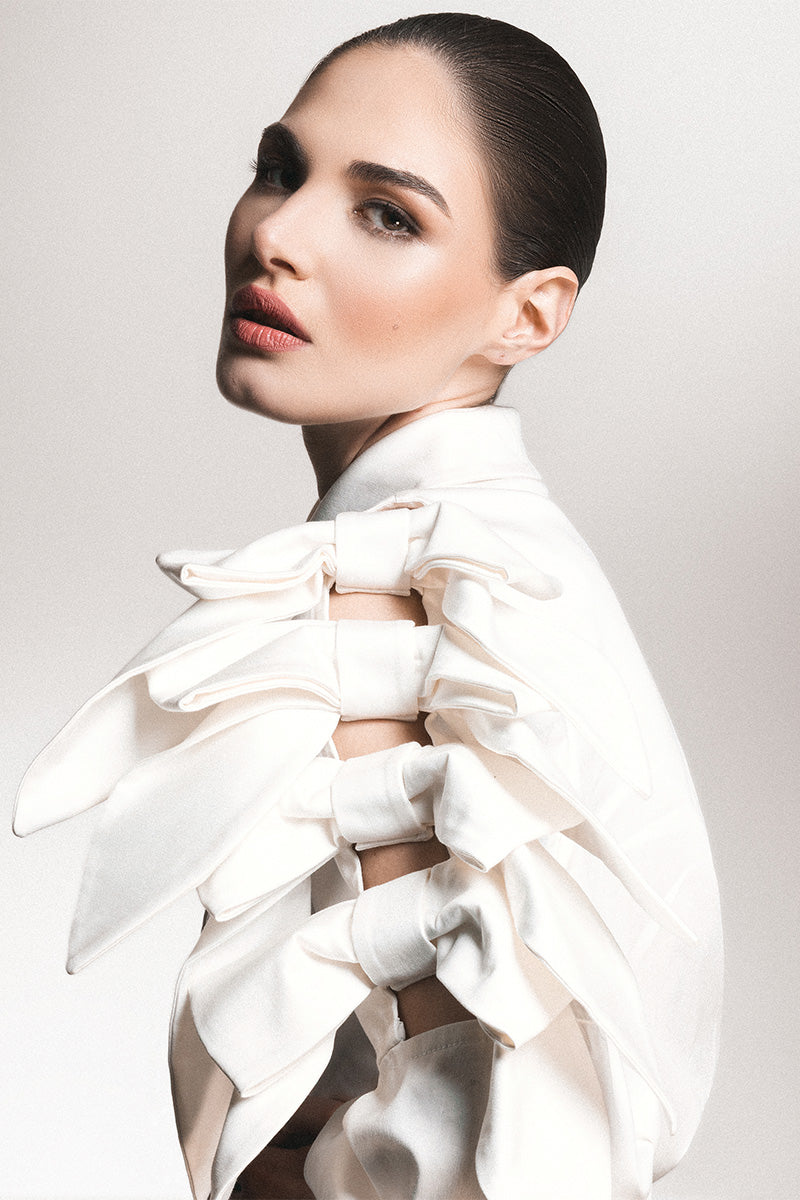 White Liya bow-sleeve shirt with long sleeves and a classic collar, displayed on a hanger.