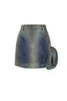 Back view of NADYA DZYAK denim mini skirt with rust-colored decorative accents on a model.