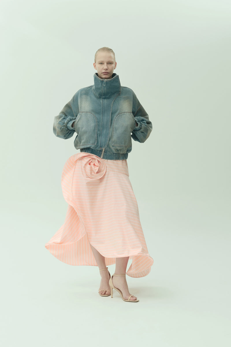 NADYA DZYAK midi skirt with 3D floral decor in peach, featuring elegant design and flowy fabric, modeled on a woman.